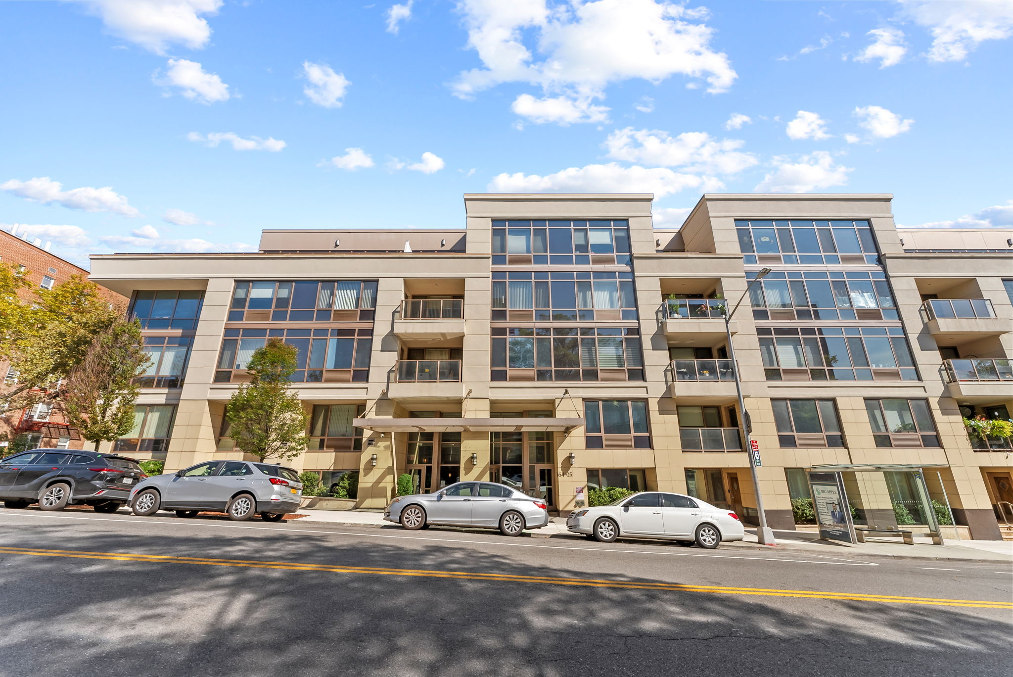 64-05 Yellowstone Boulevard, Unit 414 Queens, NY 11375 - Photo 13 of 14 a front view of a building with lot of cars and trees
