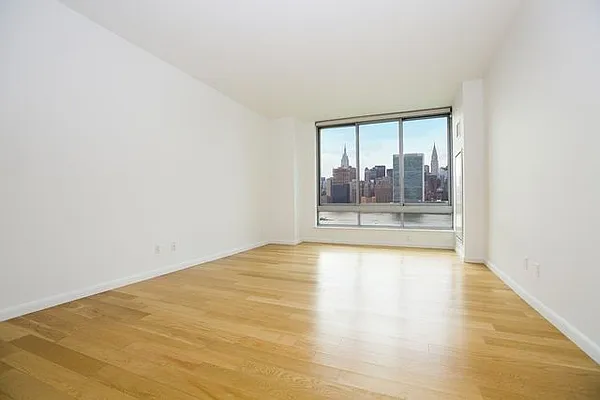 46-30 Center Boulevard, Unit 1209 Queens, NY 11109 - Photo 7 of 26 a view of an empty room with wooden floor and a window