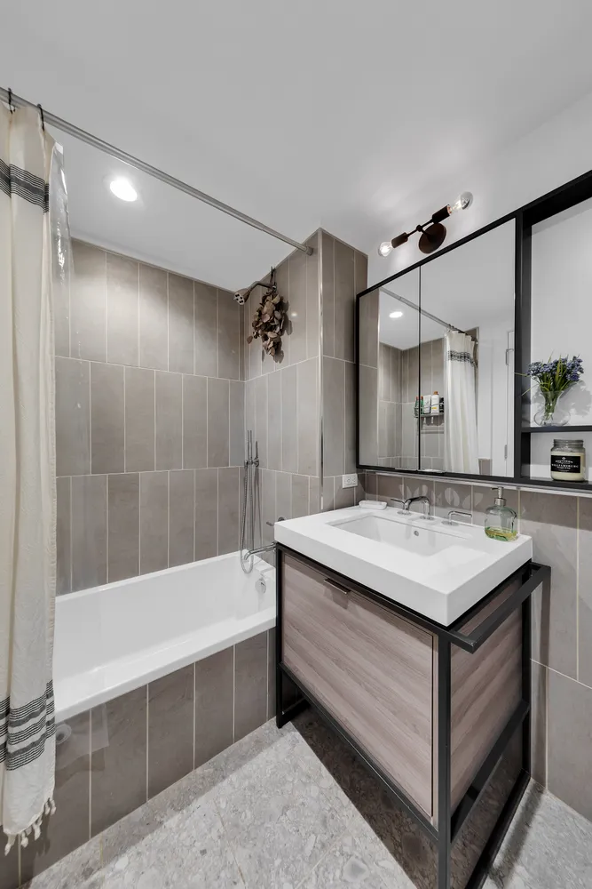 a bathroom with a tub sink shower and mirror
