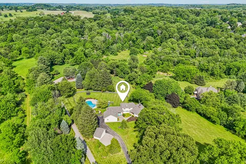 an aerial view of a residential houses with outdoor space and trees all around