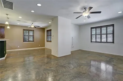 a view of an empty room with chandelier fan and fire place
