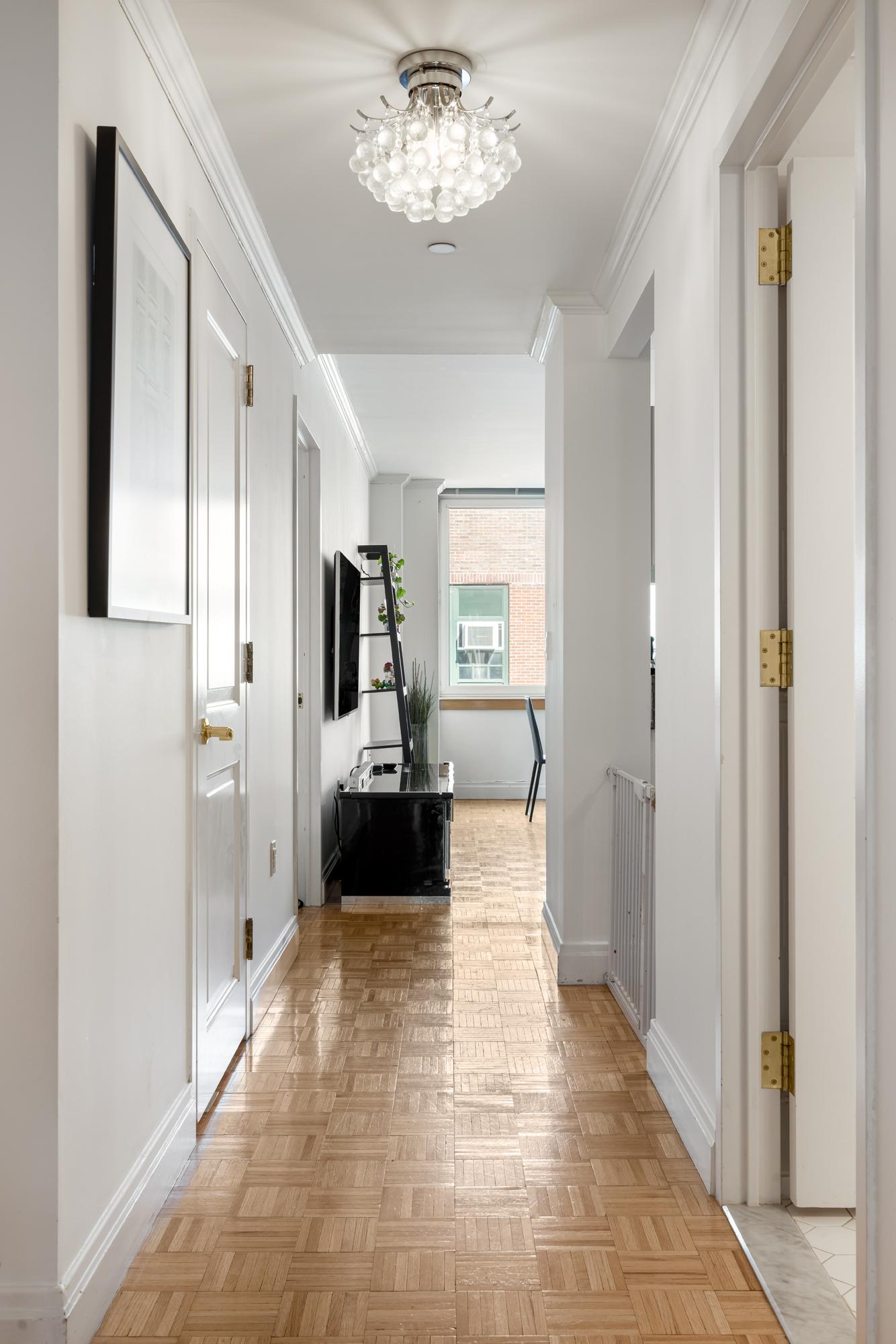 404 East 76th Street, Unit 6K Manhattan, NY 10021 - Photo 10 of 12 a view of a hallway with wooden floor and a living room