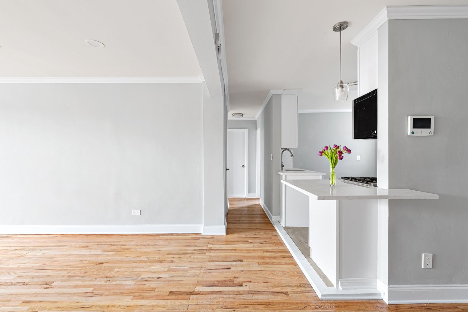 a view of a kitchen with wooden floor and white cabinets