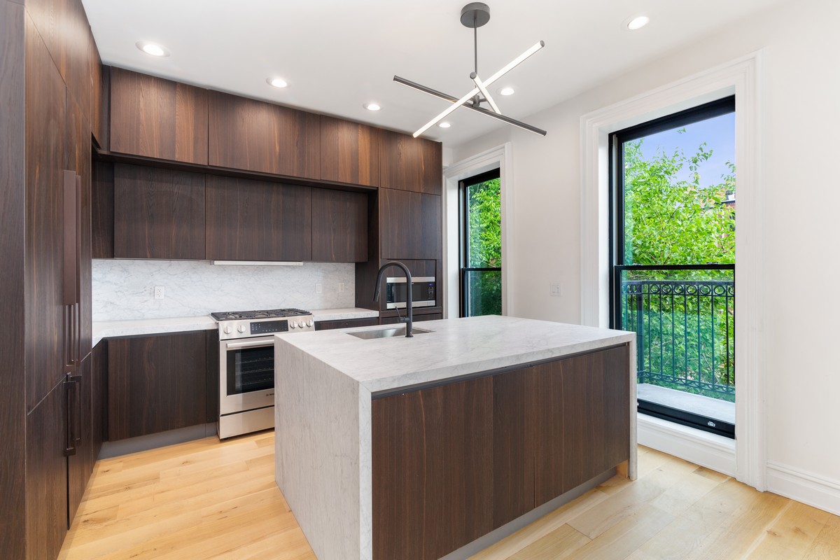 354 Macon Street, Unit 2 Brooklyn, NY 11233 - Photo 2 of 13 a kitchen with kitchen island stainless steel appliances a stove sink and microwave