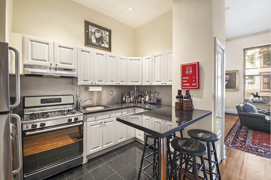 128 East 65th Street Manhattan, NY 10065 - Photo 7 of 10 a kitchen with granite countertop a stove a sink and cabinets