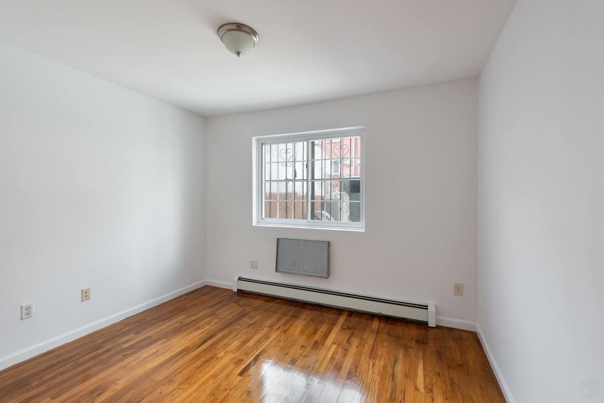 54 Lott Street, Unit 2 Brooklyn, NY 11226 - Photo 5 of 9 an empty room with wooden floor and windows