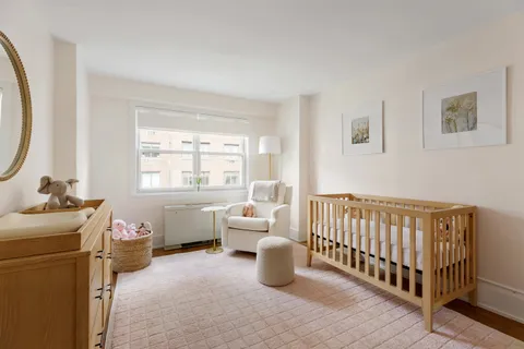 a bedroom with a baby bed a couch and a window