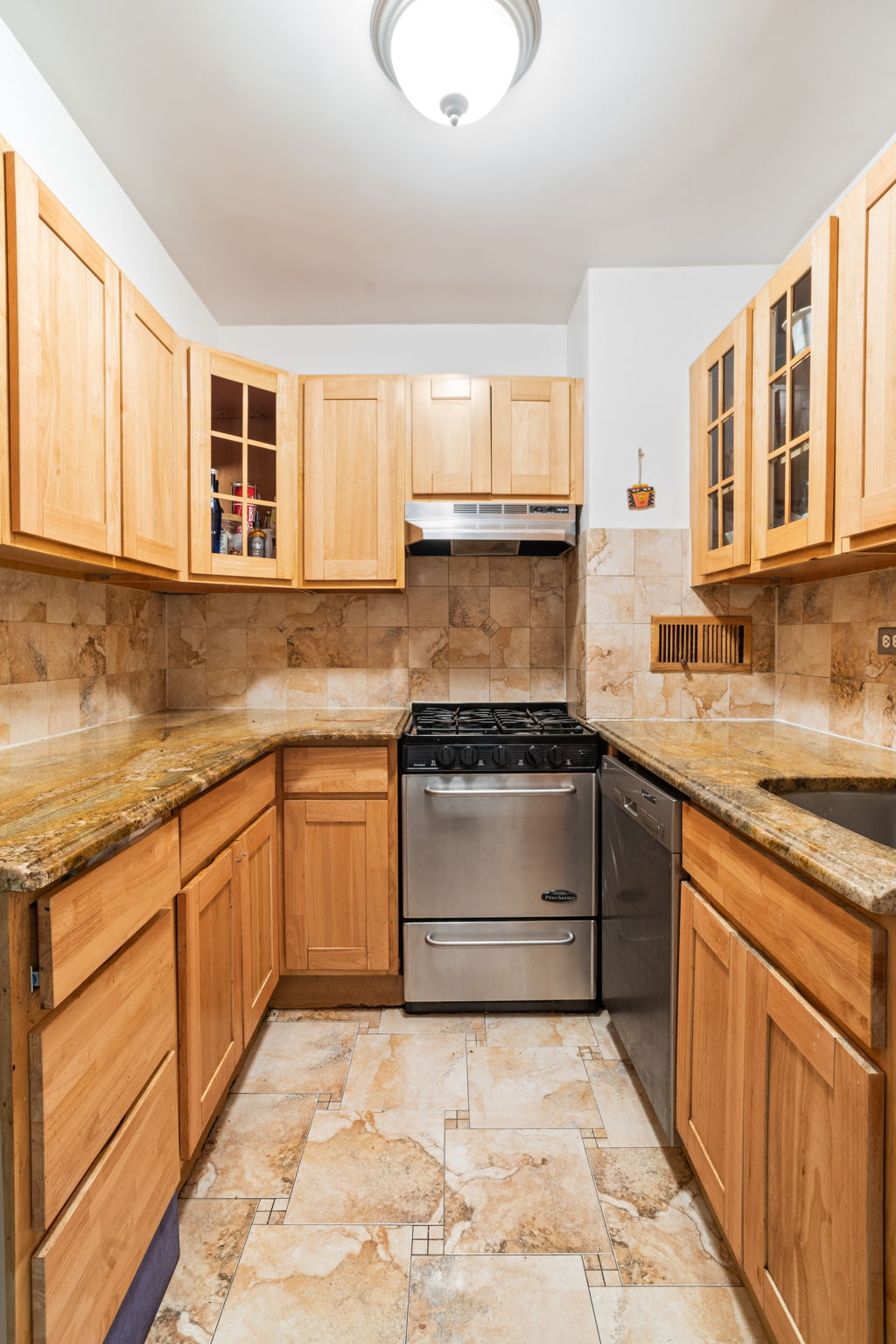 401 East 65th Street, Unit 12F Manhattan, NY 10065 - Photo 6 of 18 a kitchen with granite countertop a stove sink and cabinets