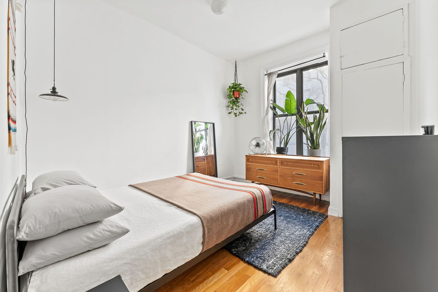 a bedroom with a bed window and mirror