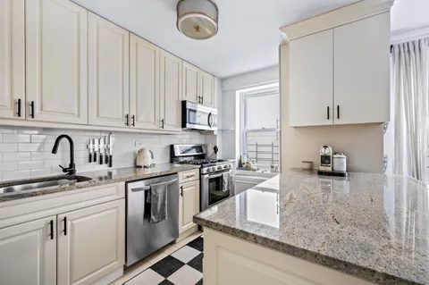 a kitchen with stainless steel appliances granite countertop a stove sink and cabinets