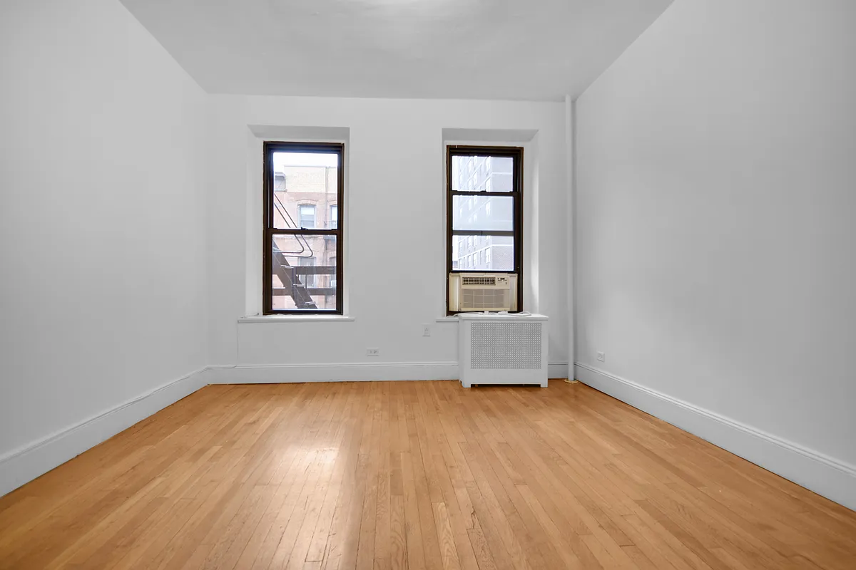 209 East 88th Street, Unit 4B Manhattan, NY 10128 - Photo 2 of 5 an empty room with wooden floor and windows