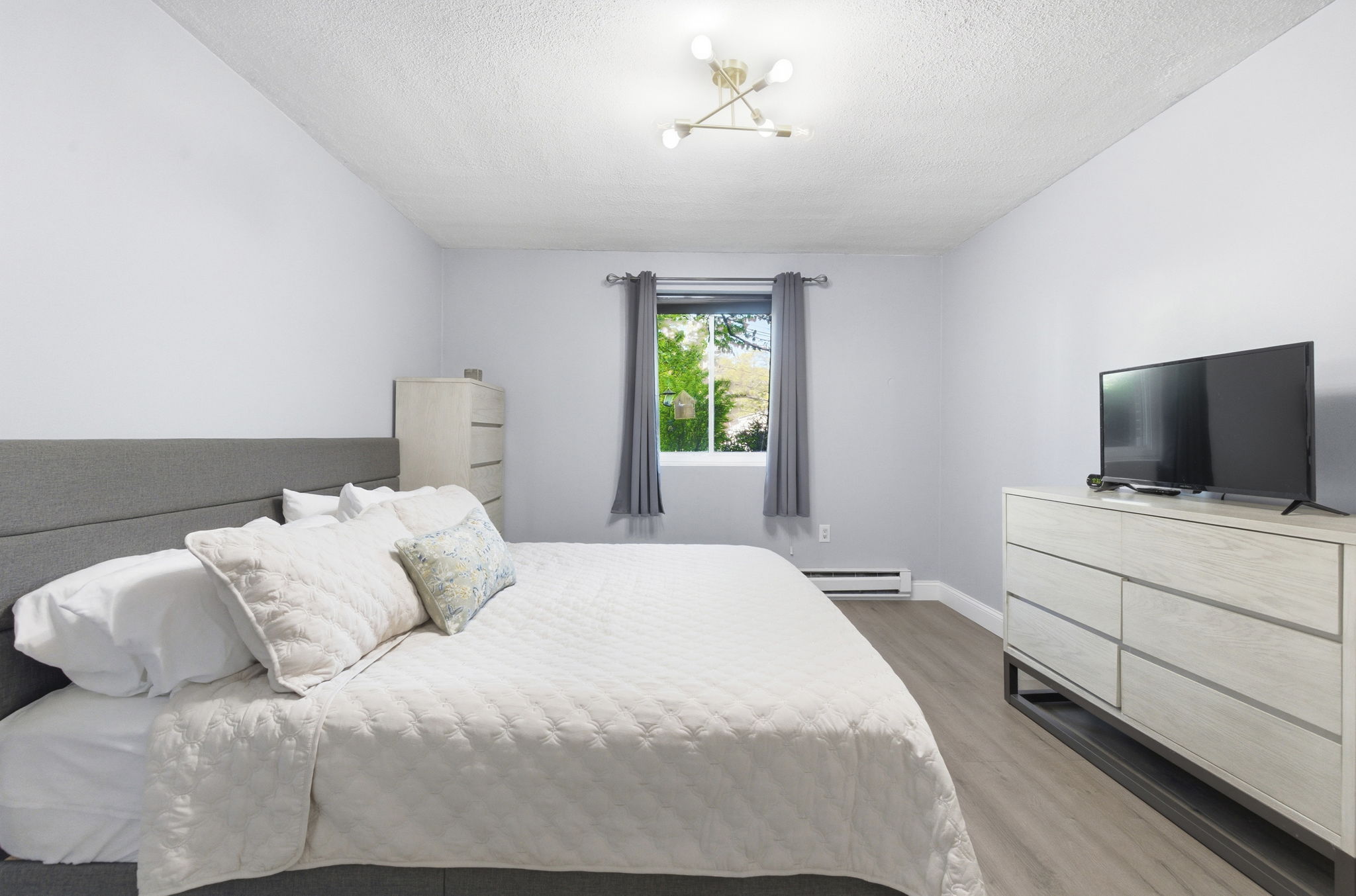 61 Wright Street, Unit 102 Stoneham, MA 02180 - Photo 17 of 26 a bedroom with a bed and a flat screen tv