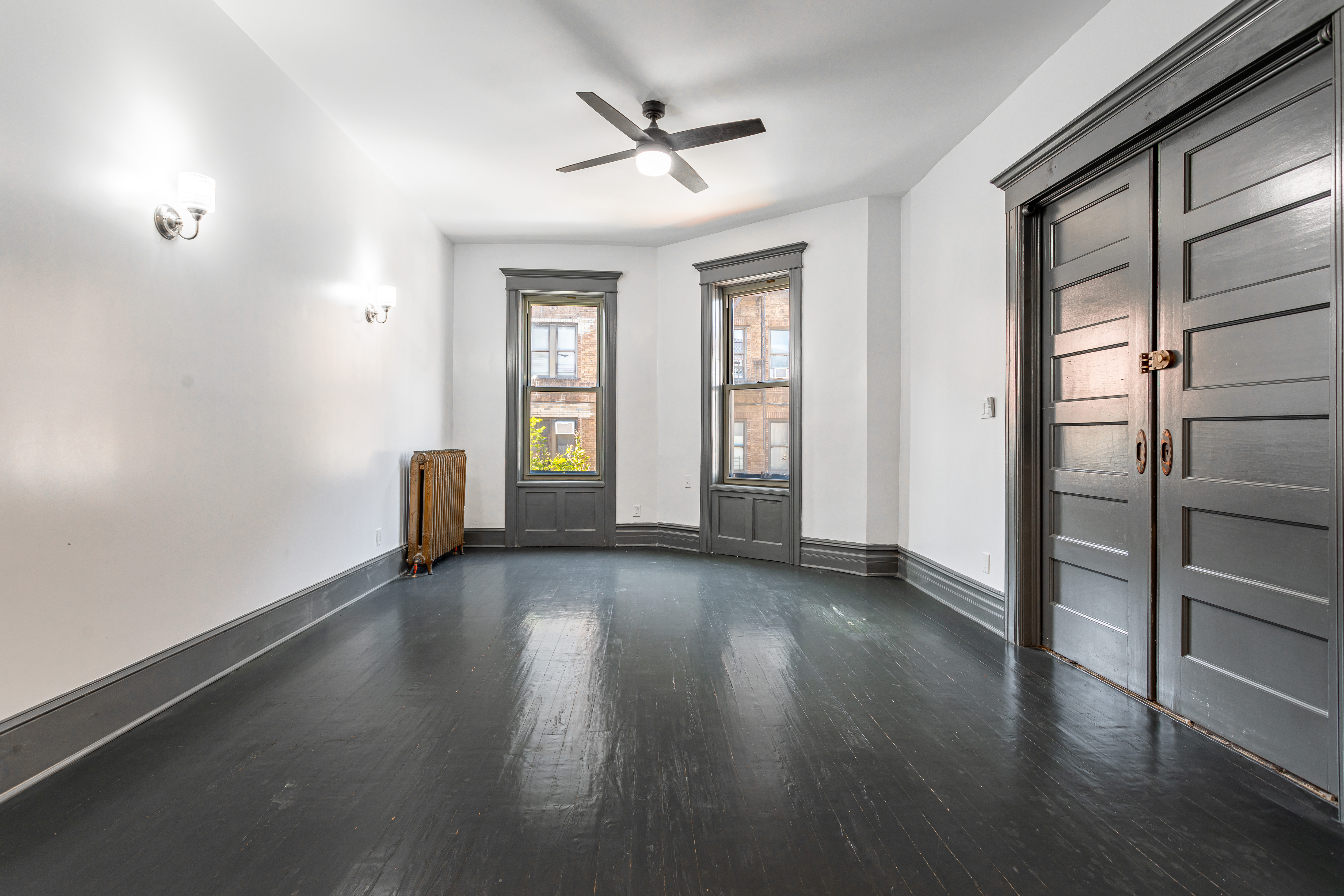 1191 Lincoln Place, Unit 1 Brooklyn, NY 11213 - Photo 2 of 13 an empty room with wooden floor and a ceiling fan