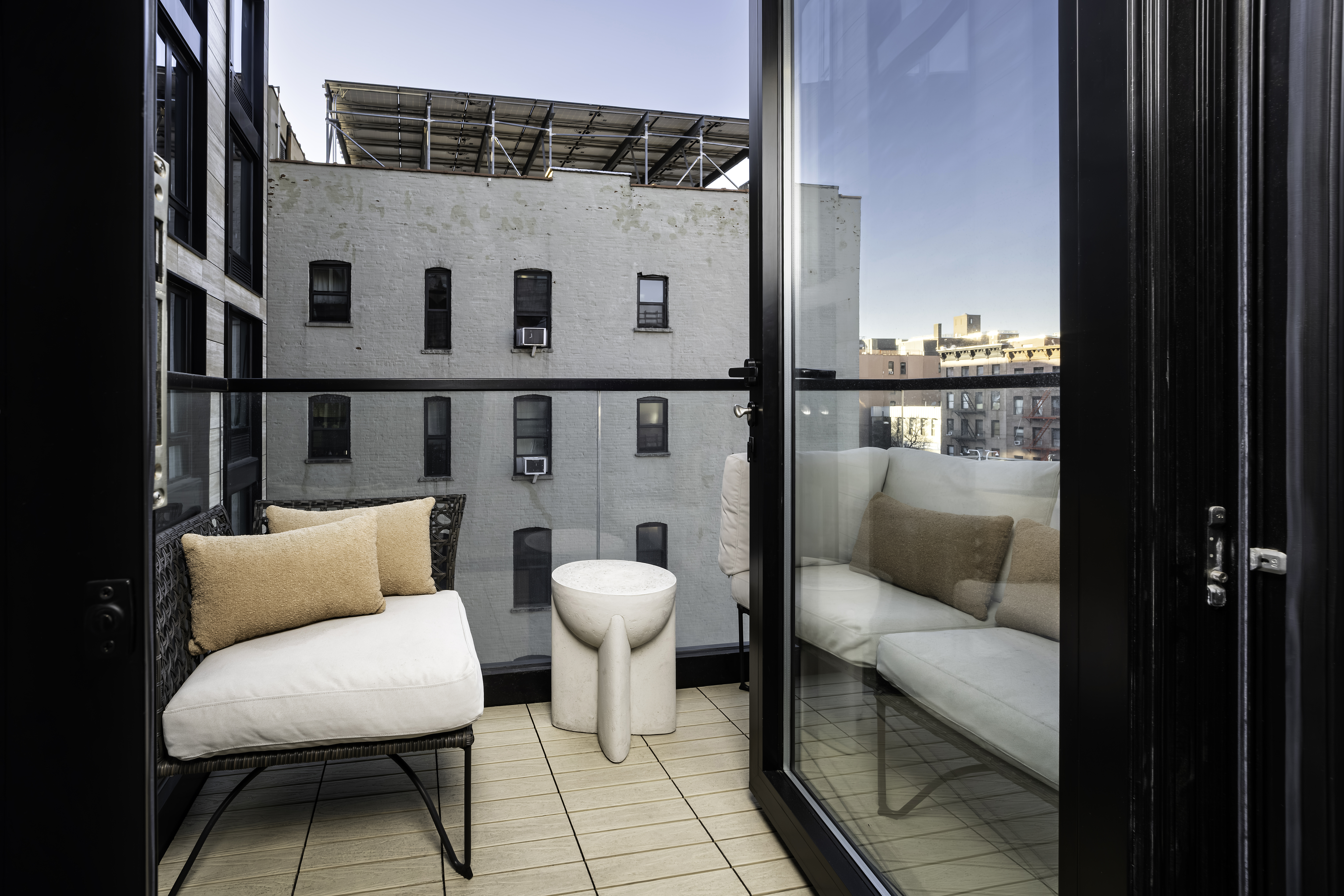 181 East 101st Street, Unit 701 Manhattan, NY 10029 - Photo 11 of 16 a balcony with a couch and a potted plant on a table