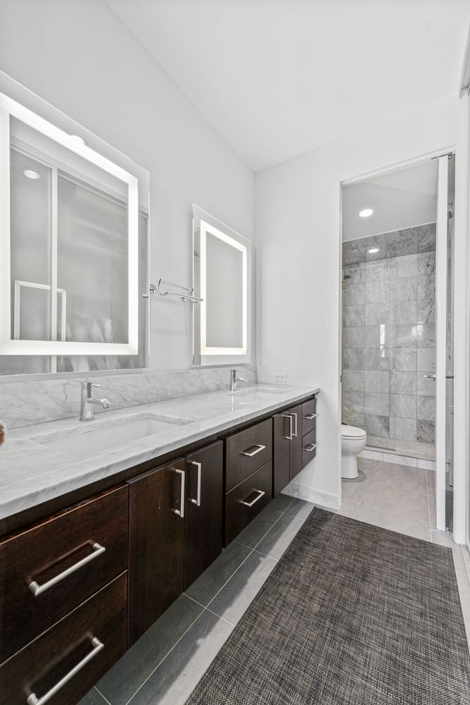 53 West 11th Street, Unit 4R/5R Manhattan, NY 10011 - Photo 6 of 9 a spacious bathroom with a granite countertop sink a toilet a mirror and a shower