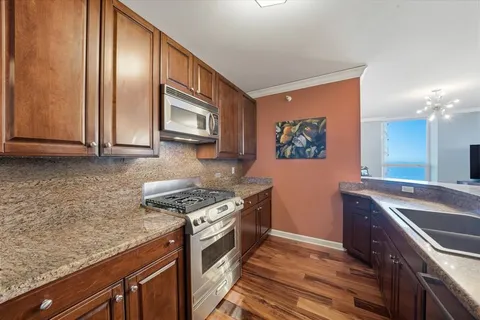 a kitchen with granite countertop stainless steel appliances a stove top oven and sink