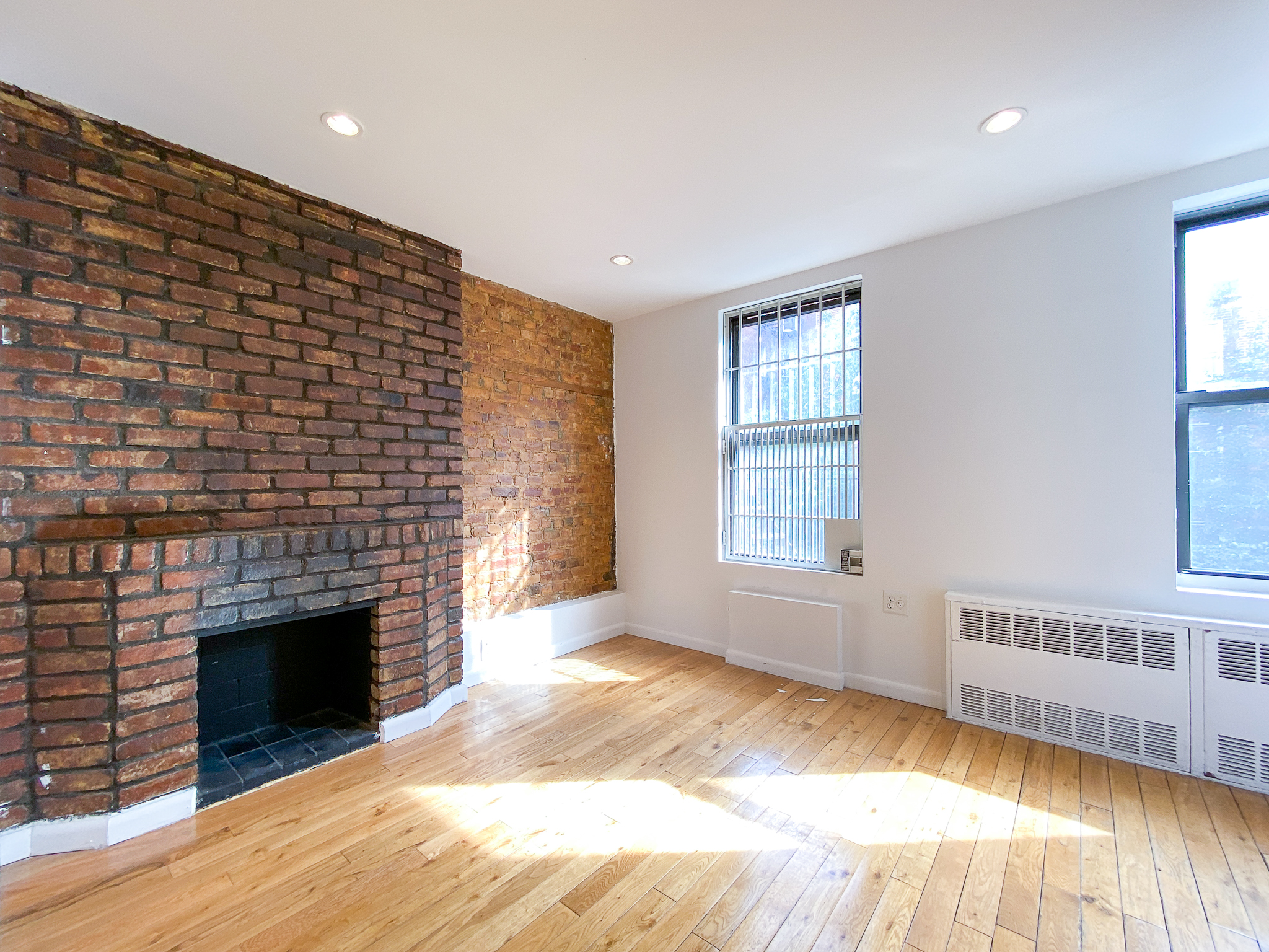 157 East 3rd Street, Unit 2B Manhattan, NY 10009 - Photo 2 of 18 a view of an empty room with wooden floor fireplace and a window