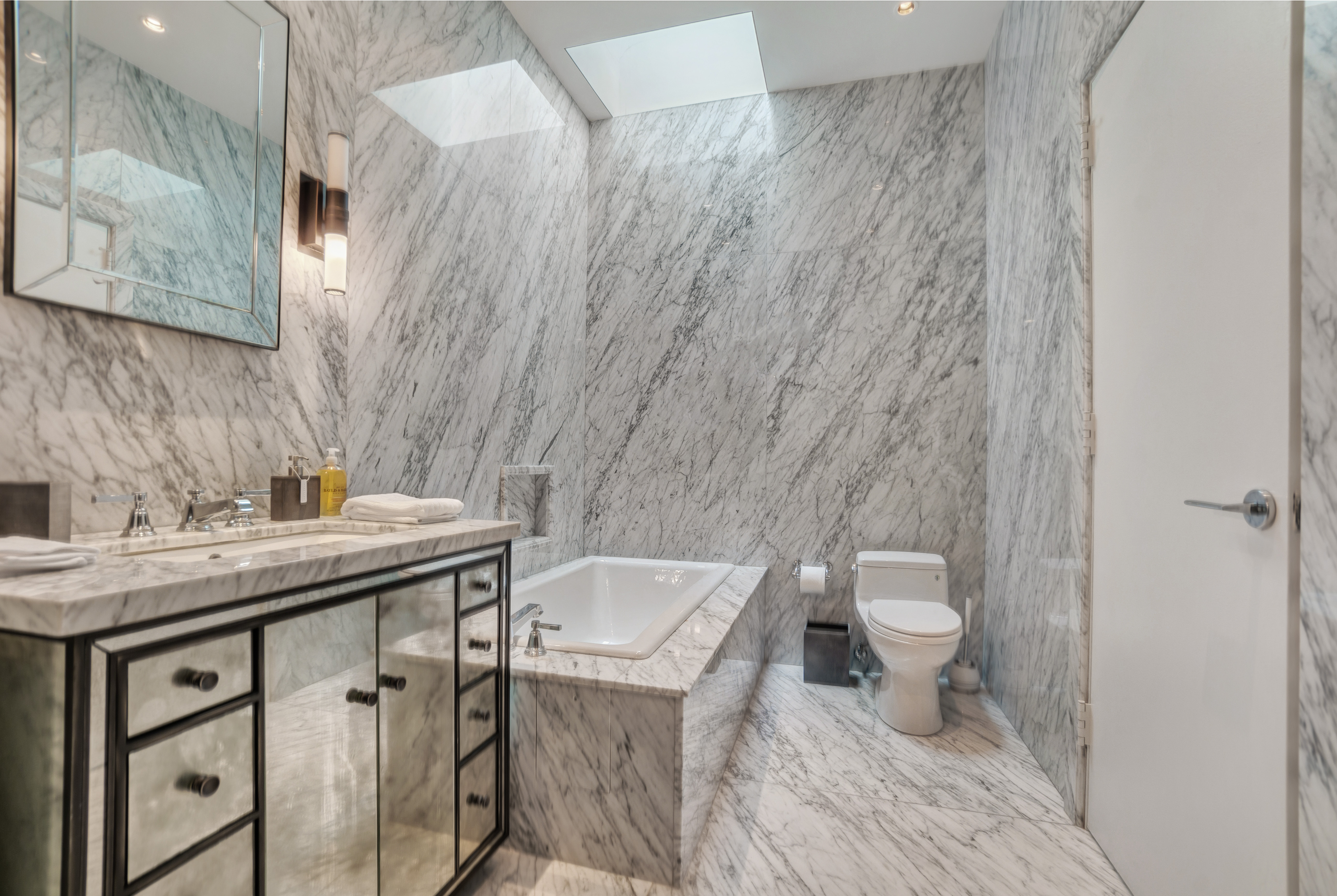 145 Spring Street, Unit PH Manhattan, NY 10012 - Photo 6 of 11 a bathroom with a sink a toilet and a mirror