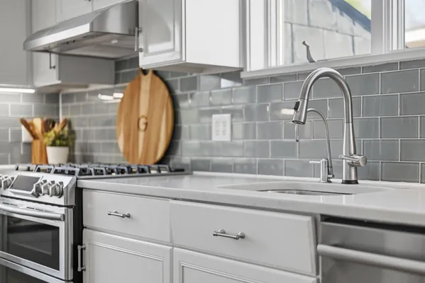 a kitchen with granite countertop a stove a sink a dining table and chairs with wooden floor