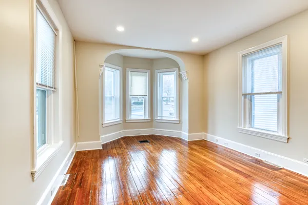 an empty room with wooden floor and windows