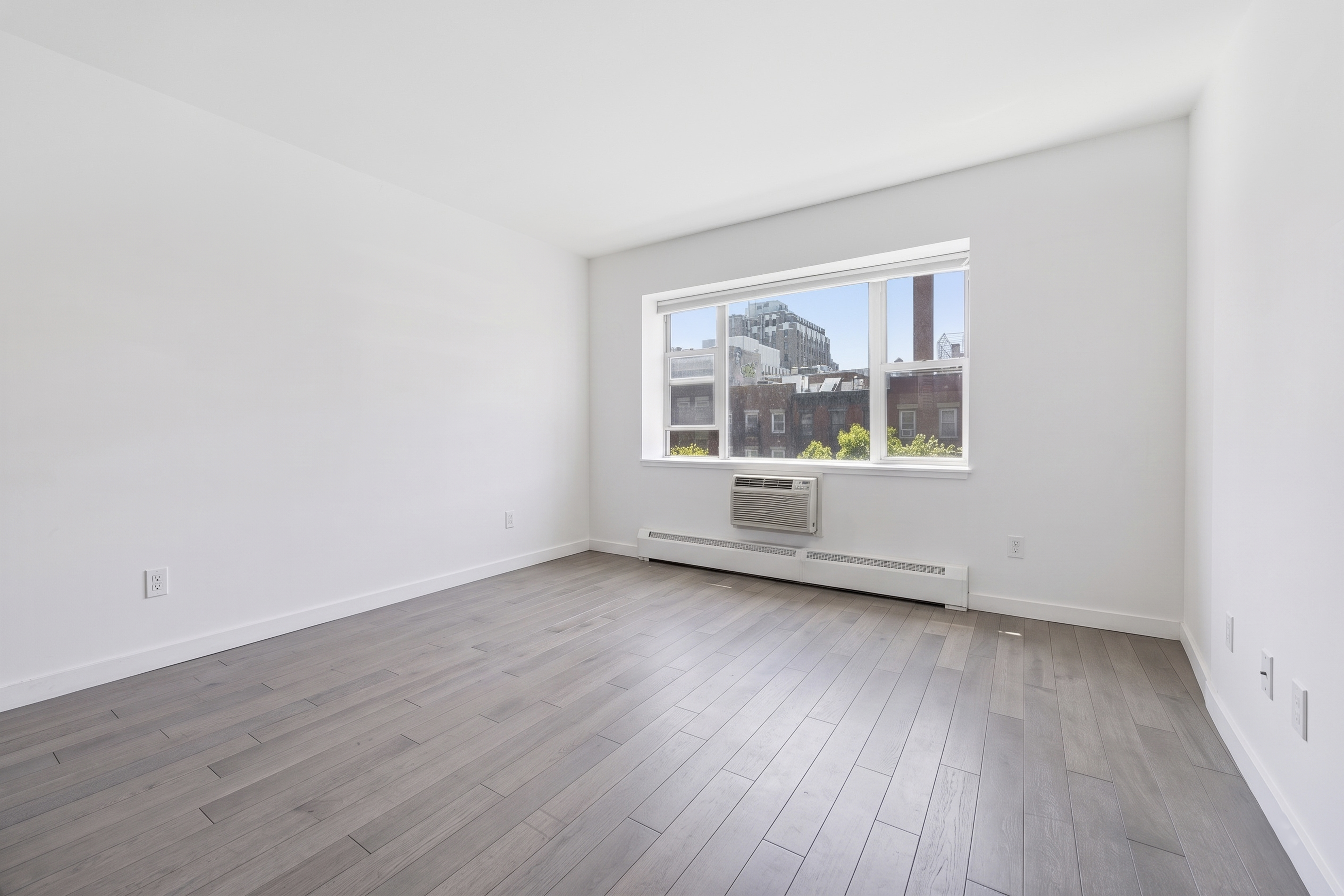 400 East 14th Street, Unit 4C Manhattan, NY 10009 - Photo 3 of 8 an empty room with wooden floor and windows
