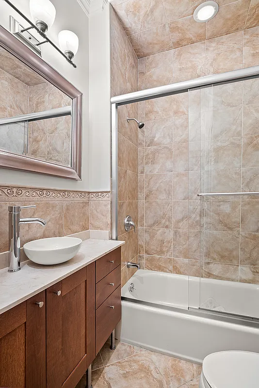 258 West 71st Street, Unit 3A Manhattan, NY 10023 - Photo 4 of 8 a bathroom with a granite countertop sink mirror toilet and bathtub