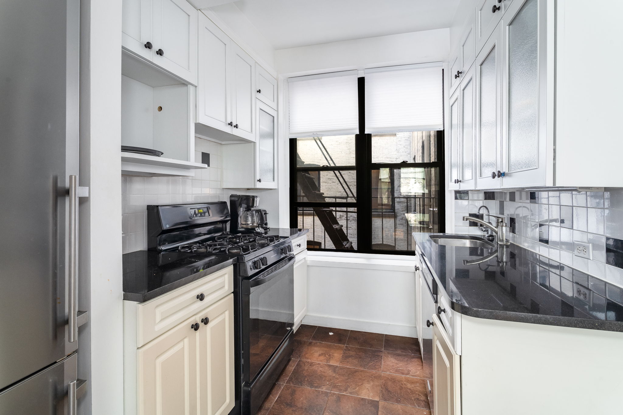 61 East 86th Street, Unit 25 Manhattan, NY 10028 - Photo 3 of 9 a kitchen with stainless steel appliances a sink stove and cabinets