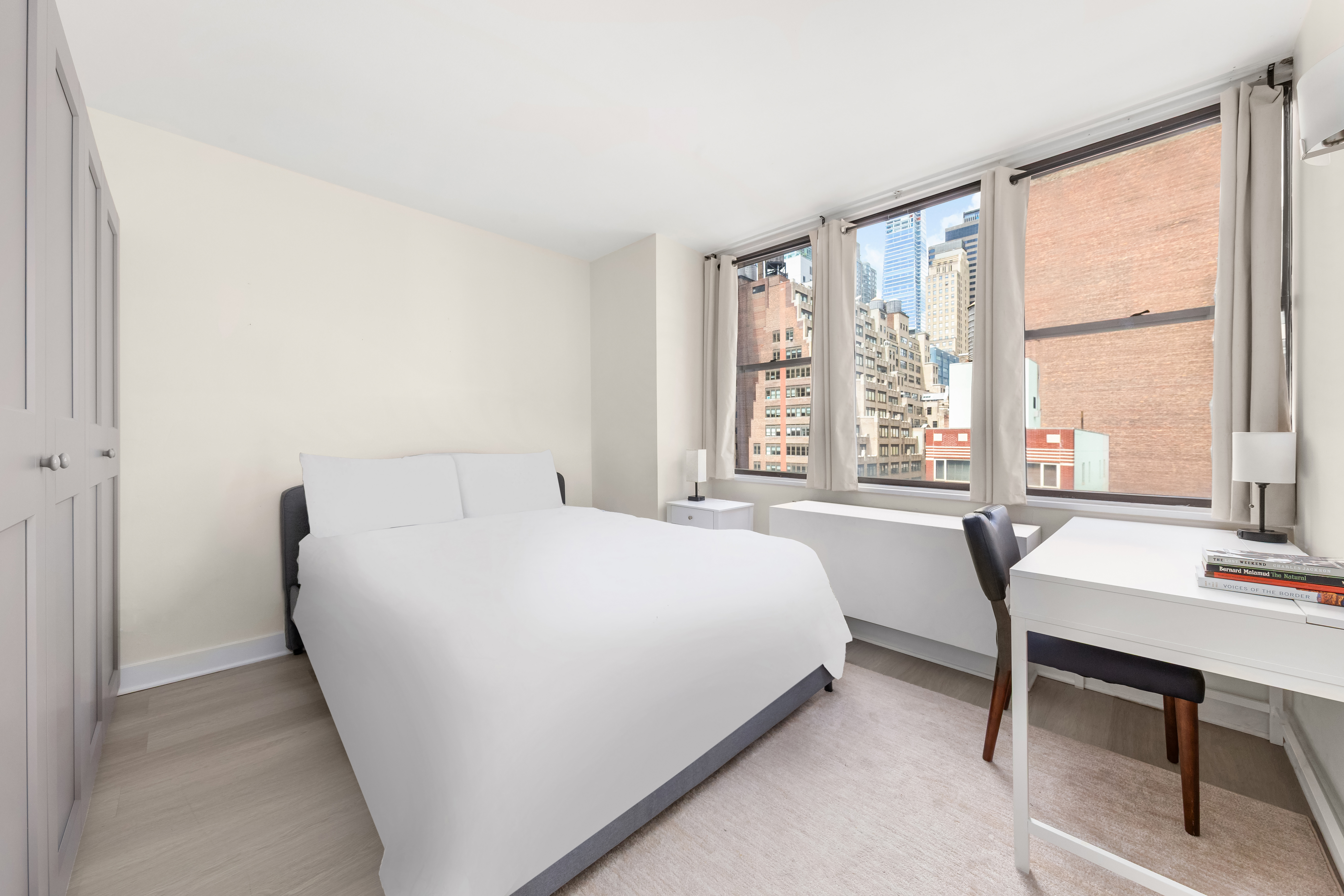 301 East 45th Street, Unit 11F Manhattan, NY 10017 - Photo 5 of 9 a bedroom with a bed table chair and a window