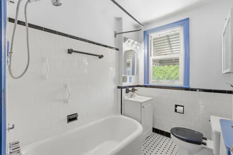 a bathroom with a bathtub a sink a window and a shower