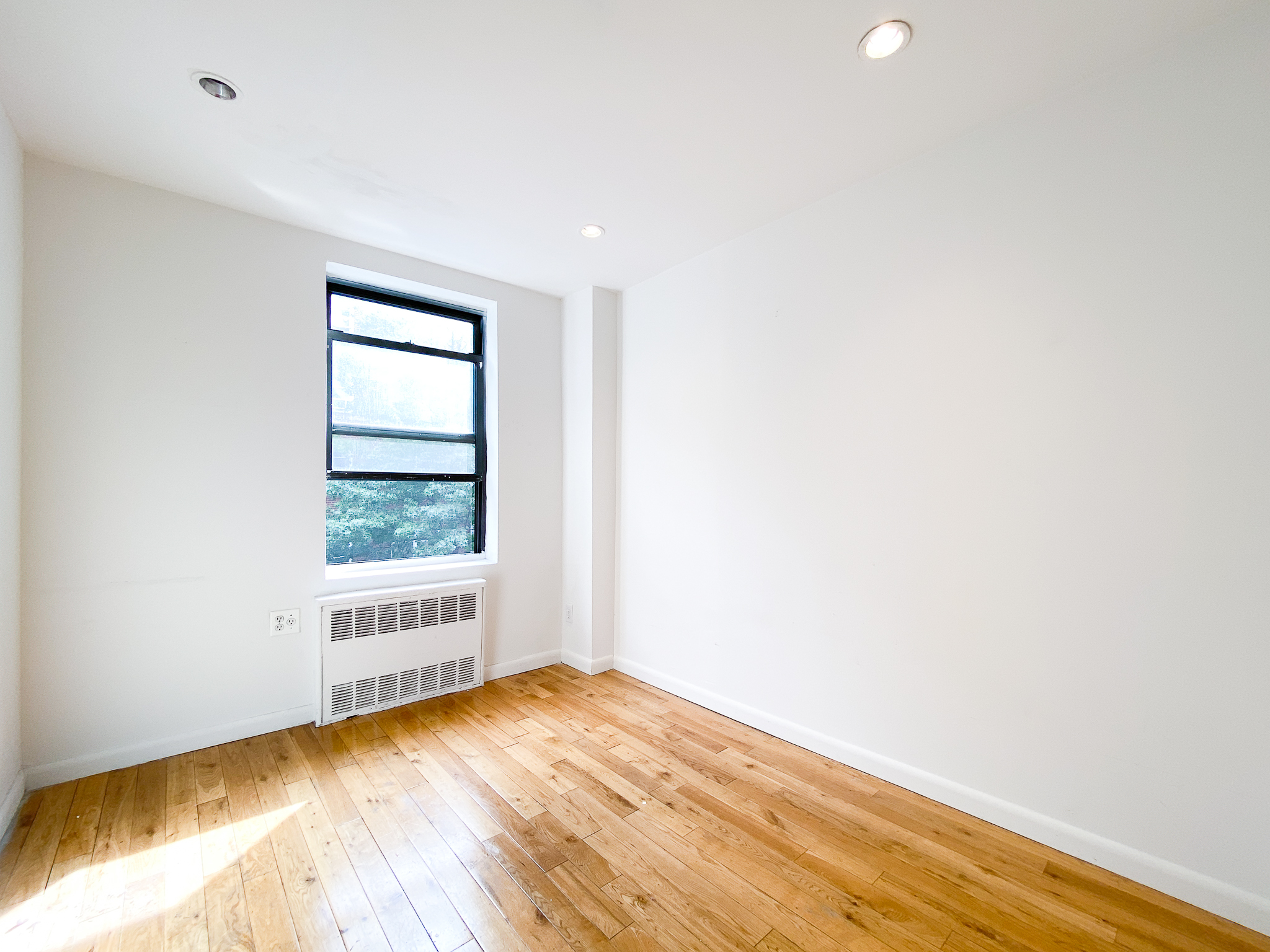 157 East 3rd Street, Unit 2B Manhattan, NY 10009 - Photo 9 of 18 a view of an empty room with wooden floor and a window
