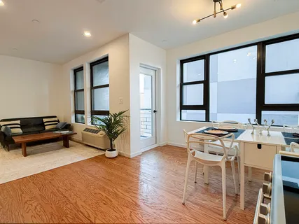 a living room with furniture a large window and wooden floor