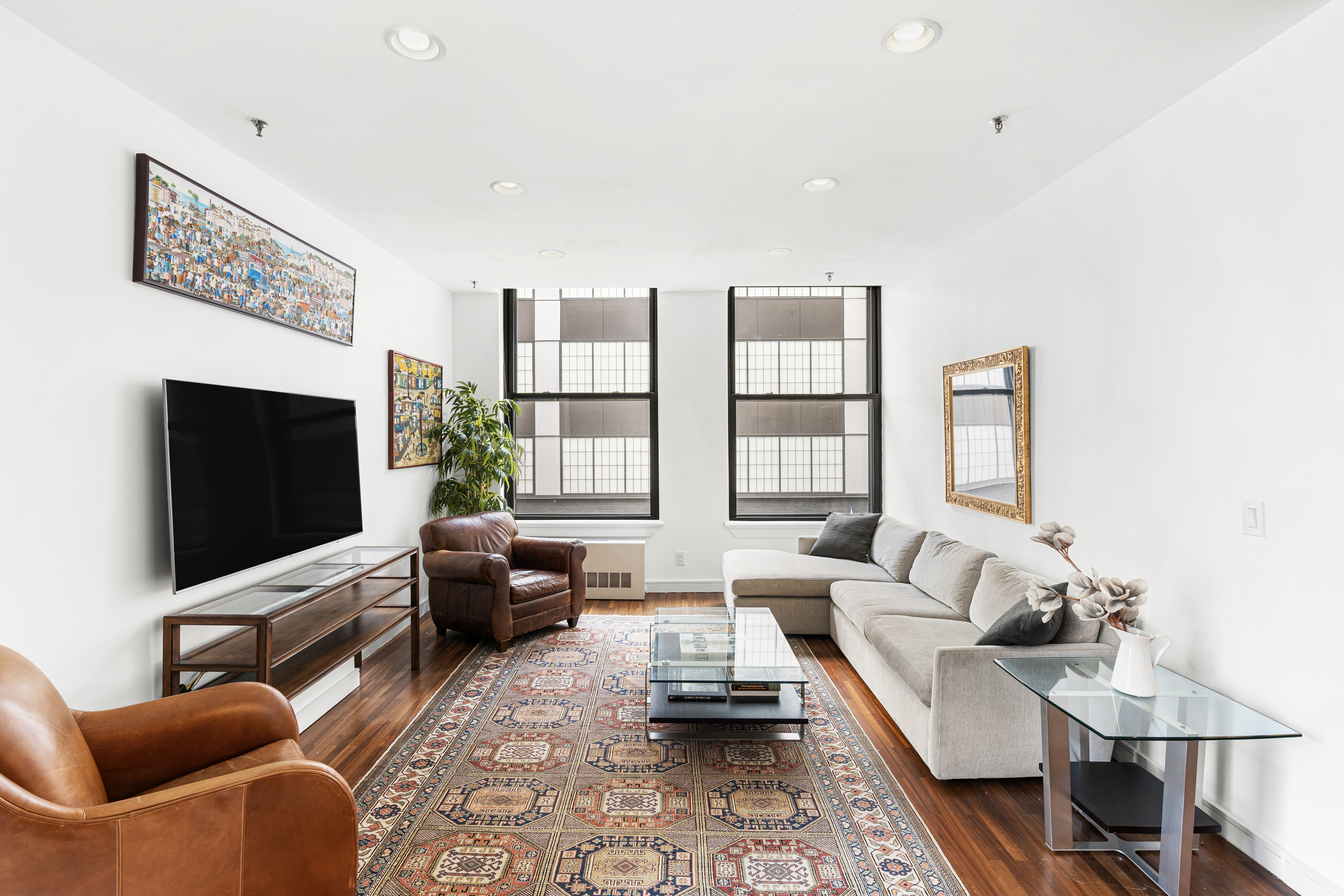 552 West 43rd Street, Unit 3A Manhattan, NY 10036 - Photo 2 of 11 a living room with furniture a flat screen tv and a large window
