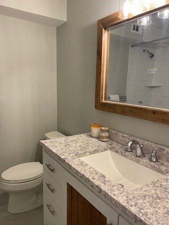 10 Beal's Cove Road, Unit E Hingham, MA 02043 - Photo 10 of 12 a bathroom with a granite countertop sink a toilet and mirror
