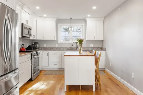 a kitchen with white cabinets and window