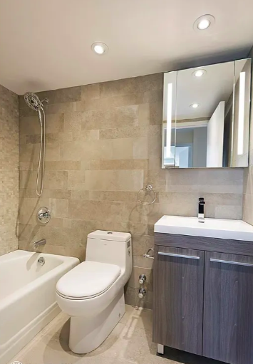 1160 3rd Avenue, Unit 18B Manhattan, NY 10065 - Photo 7 of 12 a bathroom with a toilet a sink a mirror a bathtub and vanity