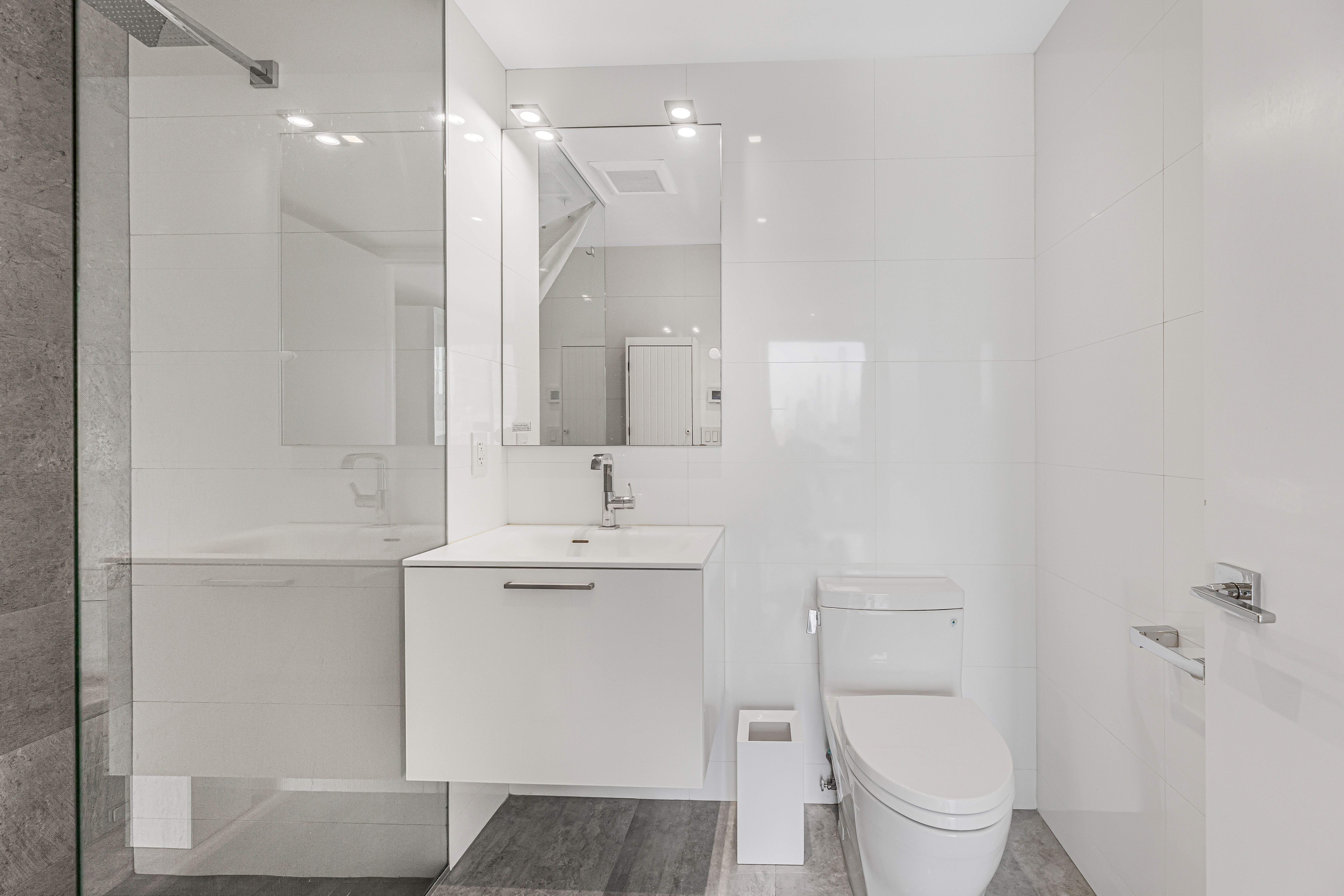 42-50 27th Street, Unit 9C Queens, NY 11101 - Photo 11 of 32 a bathroom with a toilet sink and mirror