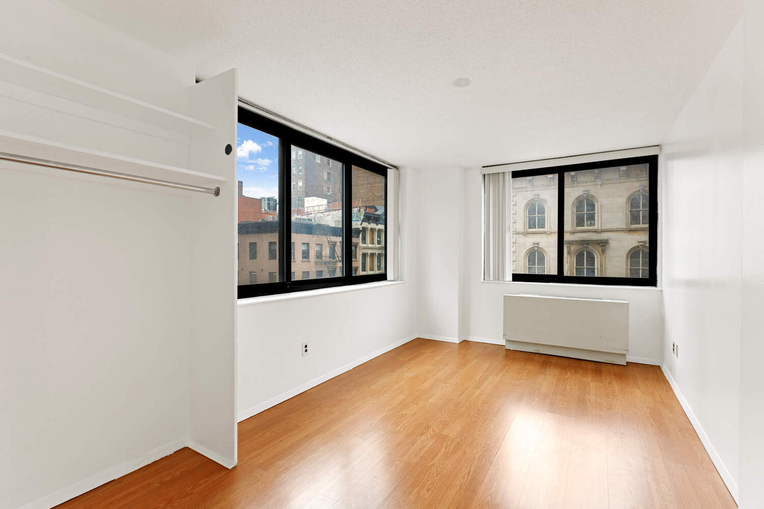 a view of an empty room with window and wooden floor