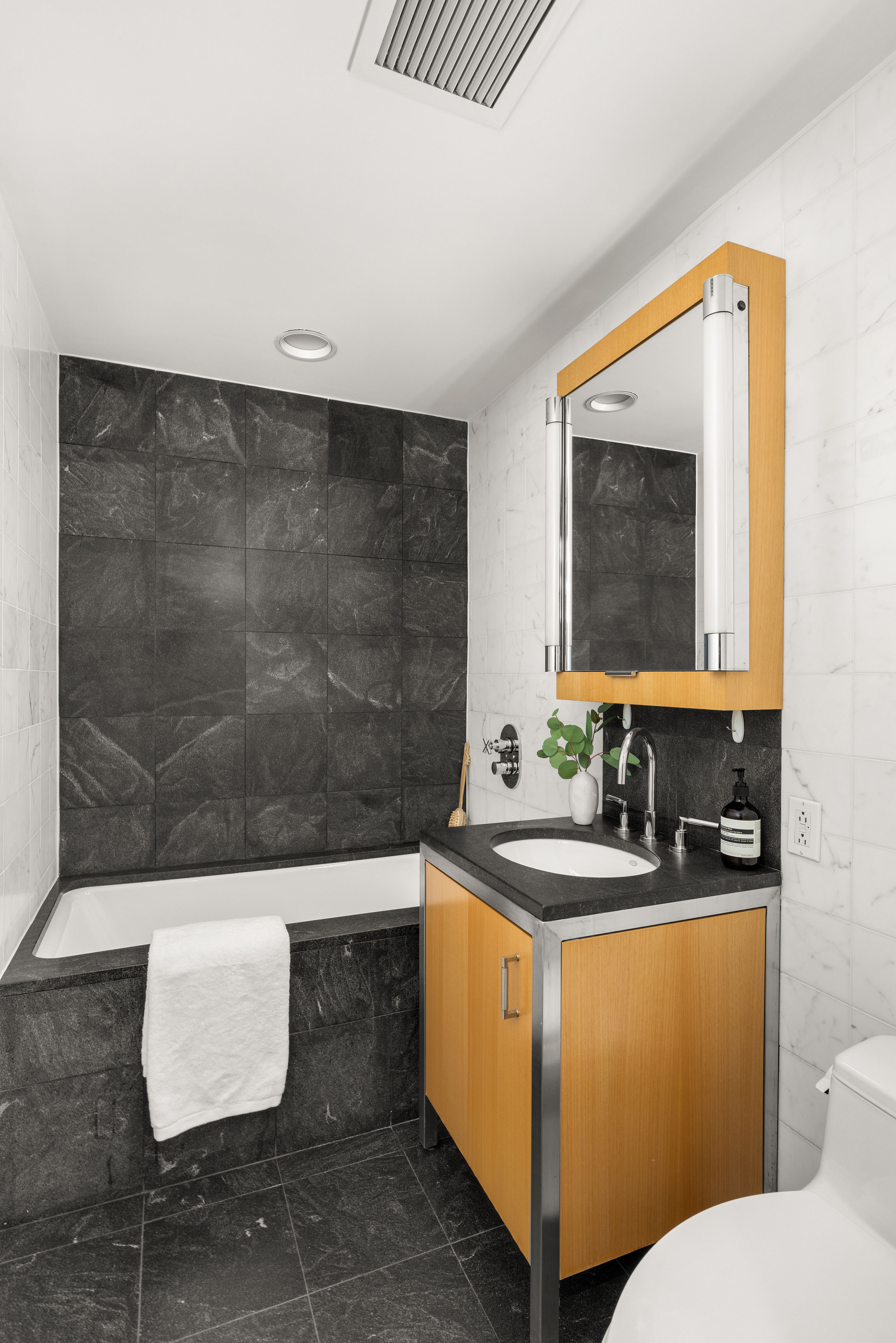 100 West 58th Street, Unit 8C Manhattan, NY 10019 - Photo 8 of 11 a bathroom with a sink a toilet and mirror