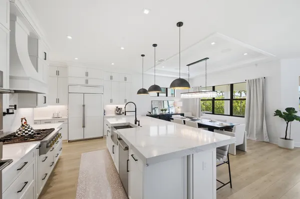 a kitchen with stainless steel appliances a stove a sink a oven a dining table and chairs