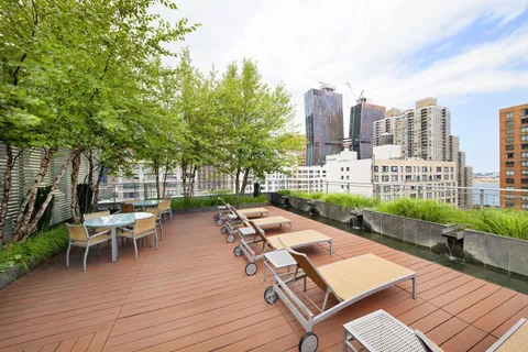 a couple of lawn chairs sitting on wooden deck with city view