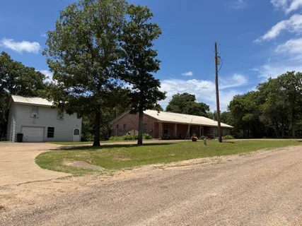 a view of a house with a big yard and palm trees