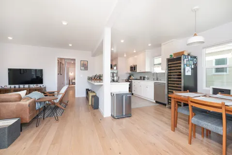 a living room with furniture a flat screen tv and kitchen view