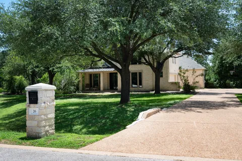 a front view of a house with a garden and trees