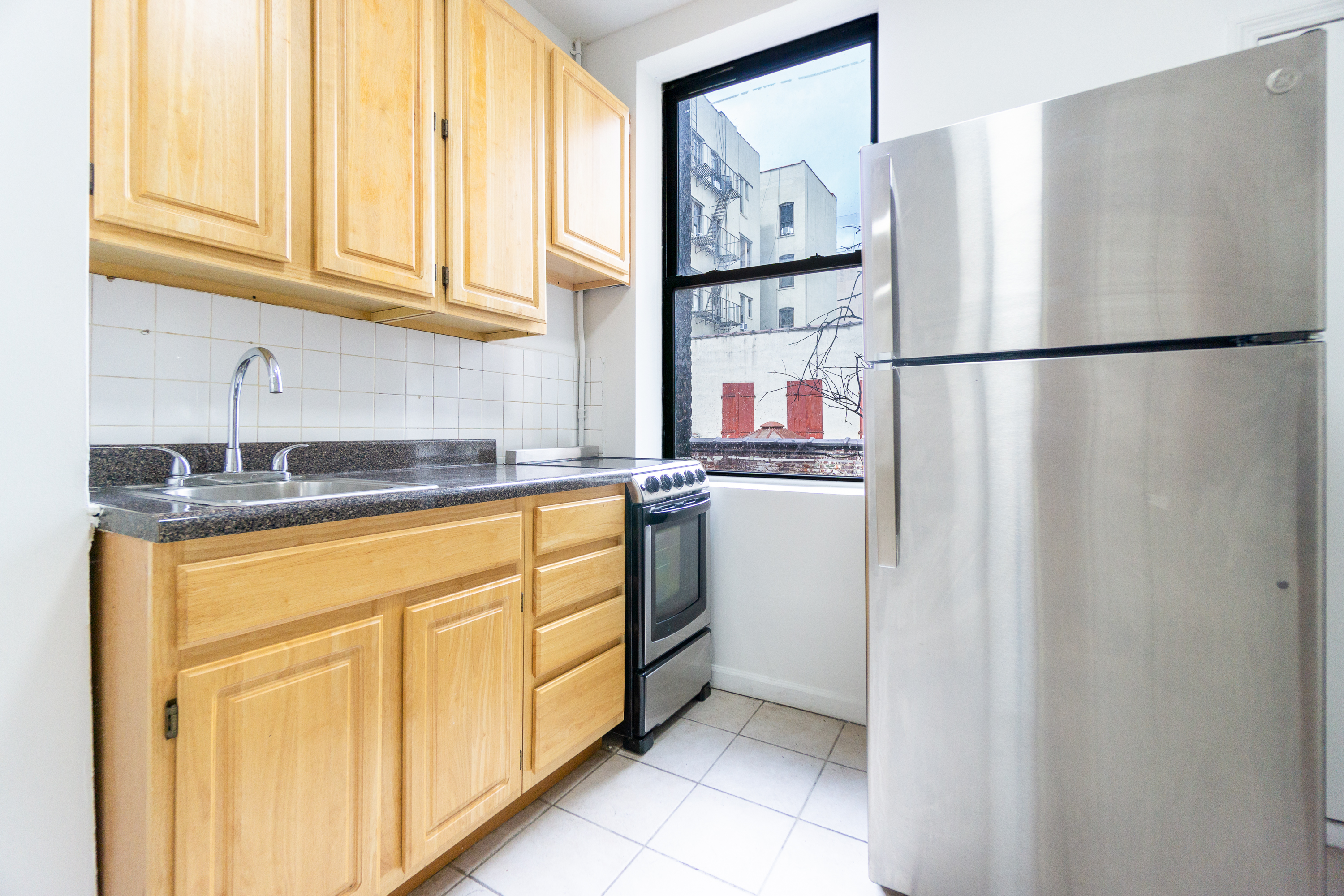 215 East 5th Street, Unit 3 Manhattan, NY 10003 - Photo 18 of 25 a kitchen with stainless steel appliances granite countertop a refrigerator sink and cabinets