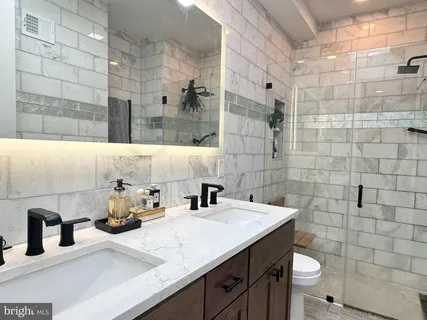 a bathroom with a granite countertop sink a toilet and shower