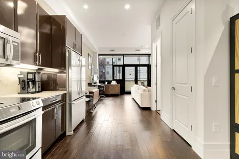 a kitchen with stainless steel appliances a refrigerator a sink dishwasher a stove and white cabinets with wooden floor