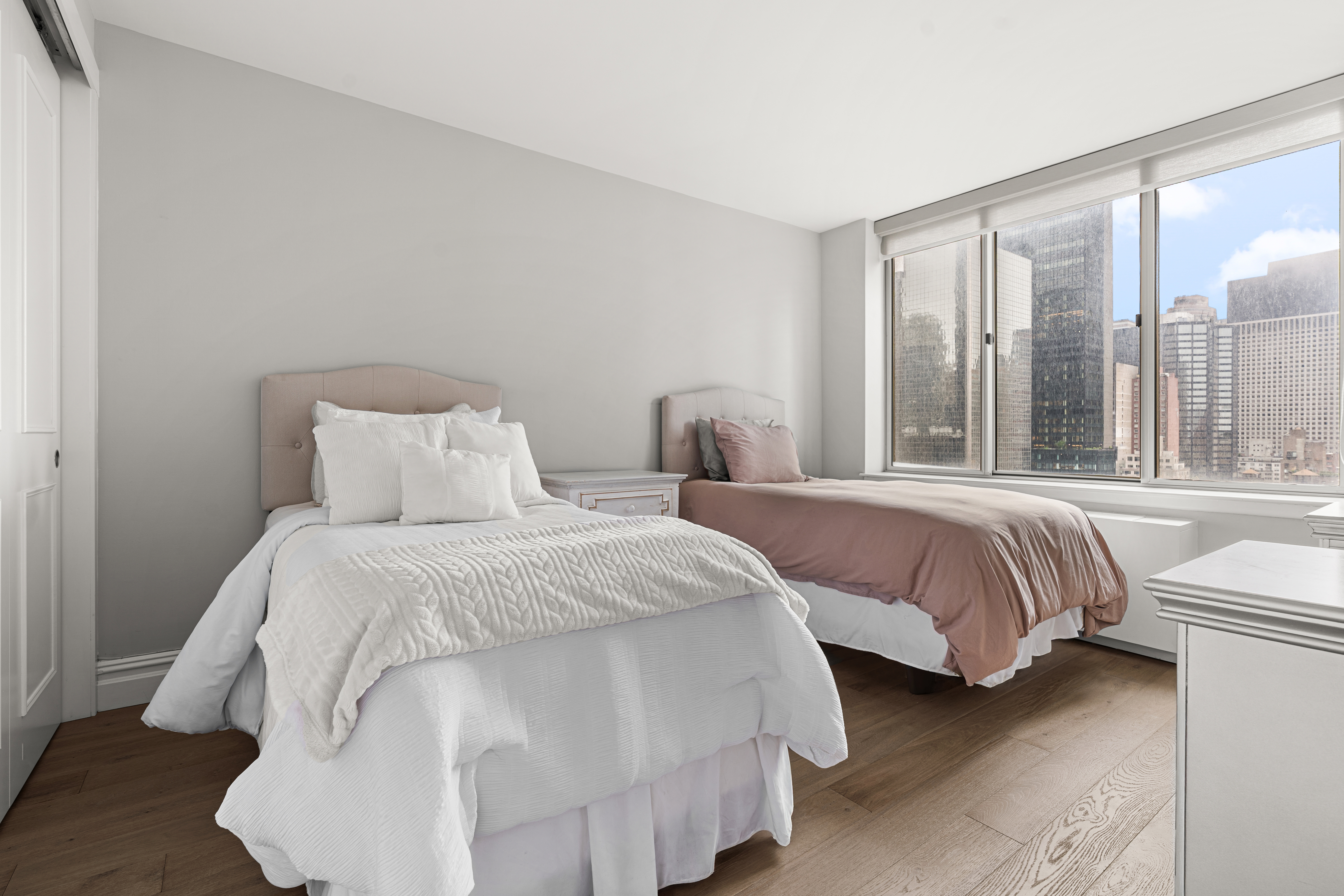 236 East 47th Street, Unit 17C Manhattan, NY 10017 - Photo 2 of 11 a bedroom with two beds and large window