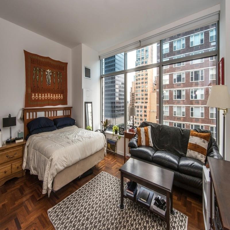 250 East 54th Street, Unit 22B Manhattan, NY 10022 - Photo 3 of 11 a bedroom with a bed a couch and a large window
