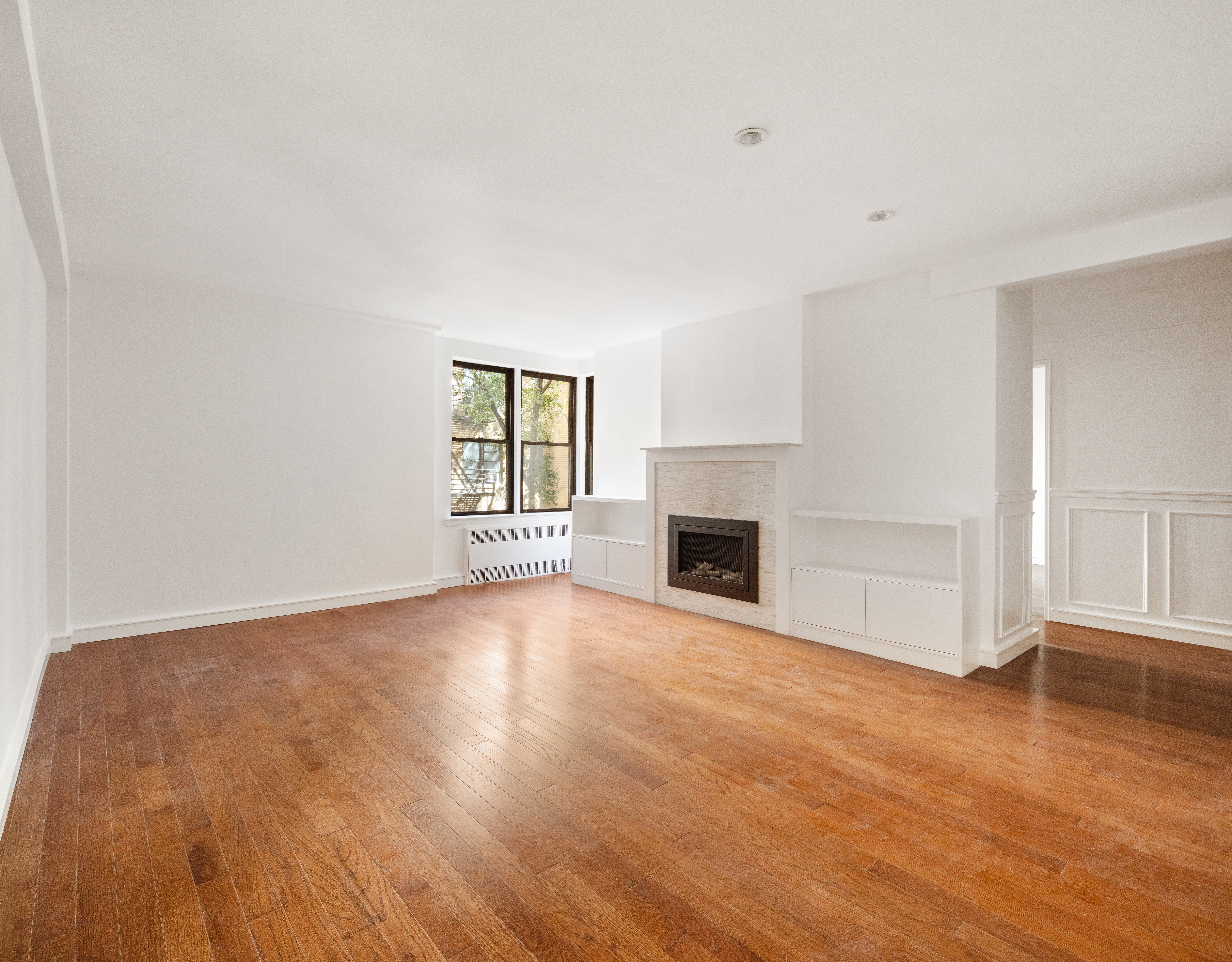 30 East 9th Street, Unit 2II Manhattan, NY 10003 - Photo 4 of 10 a view of empty room with wooden floor and fireplace