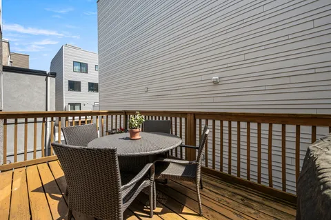 a roof deck with a dining table and chairs with wooden floor